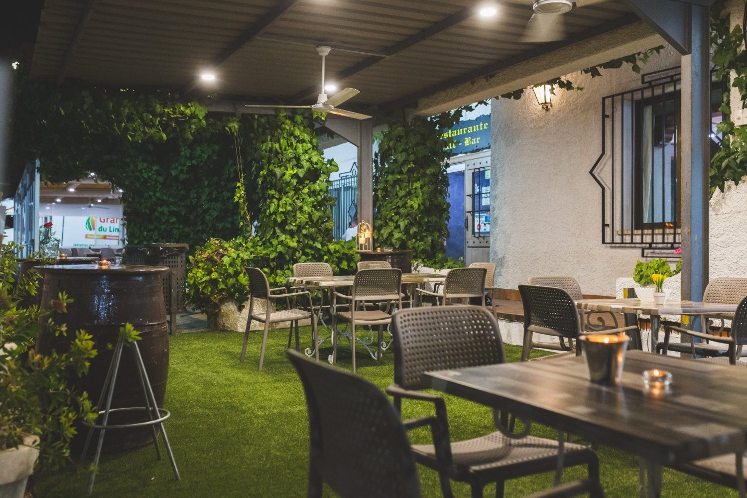 Terraza ajardinada de Hotel Casa Lorenzo, con hiedra y mesas de barrica al anochecer
